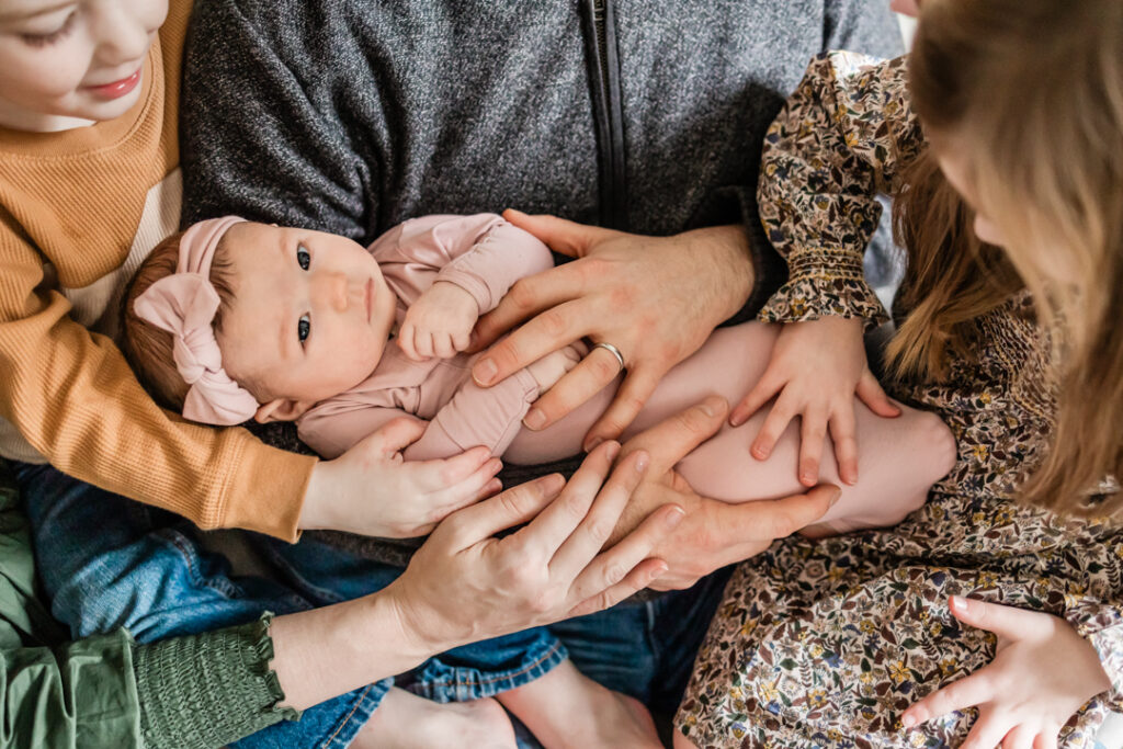 Family's hands embracing baby girl