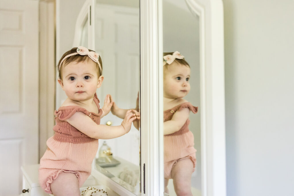 Baby girls standing in front of mirror