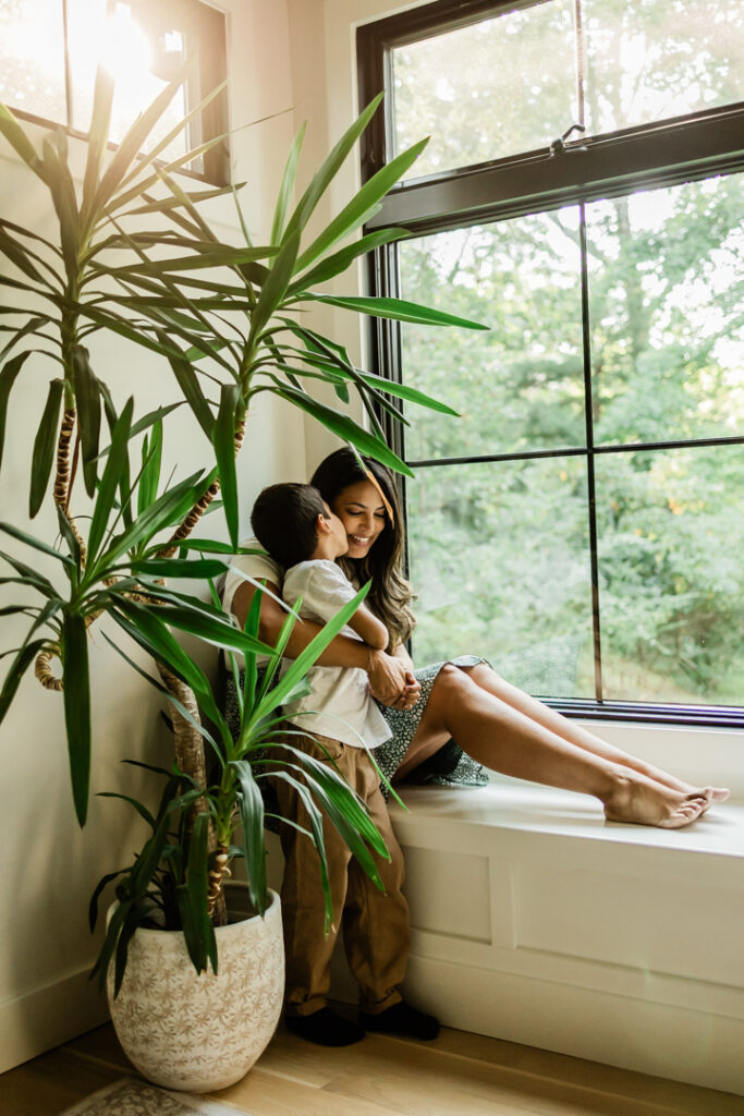 Meaningful family photos at home with little boy kissing mother as beautiful light streams through the windows