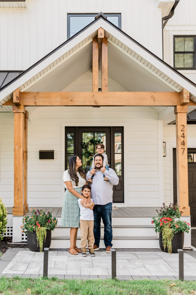 Family standing in front of their custom built home during a front porch photoshoot in Scotch Plains, NJ