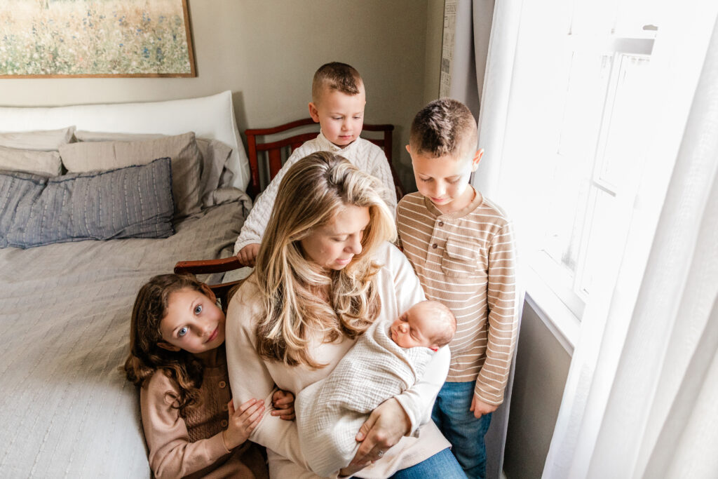 Mother holding newborn baby and surrounded by her children