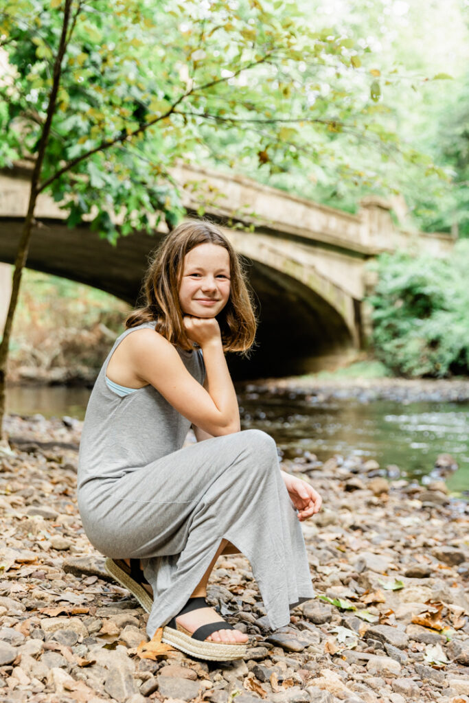 Teen girl kneeling by river in Somerset County, NJ-Natirar