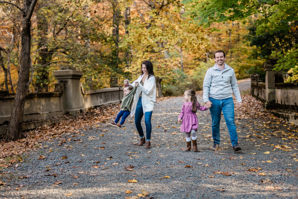 Family with little girls smiling joyfully and walking in the woods in Somerset County, NJ