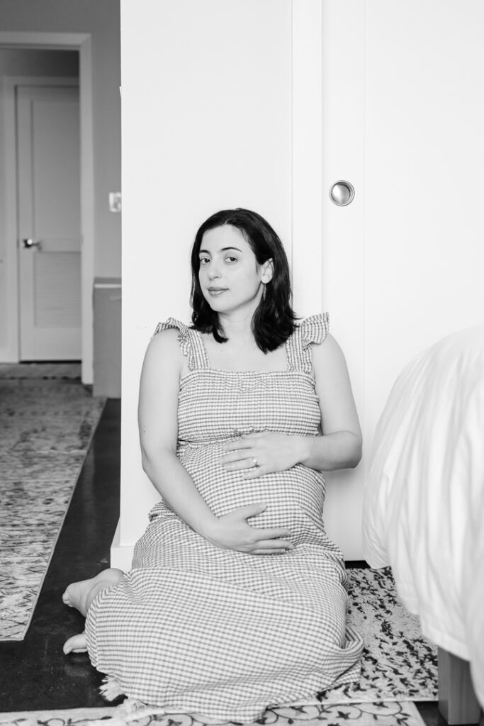 Black and while image of pregnant mom sitting on the floor