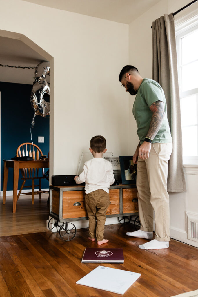 toddler helping dad play a record during newborn photo session
