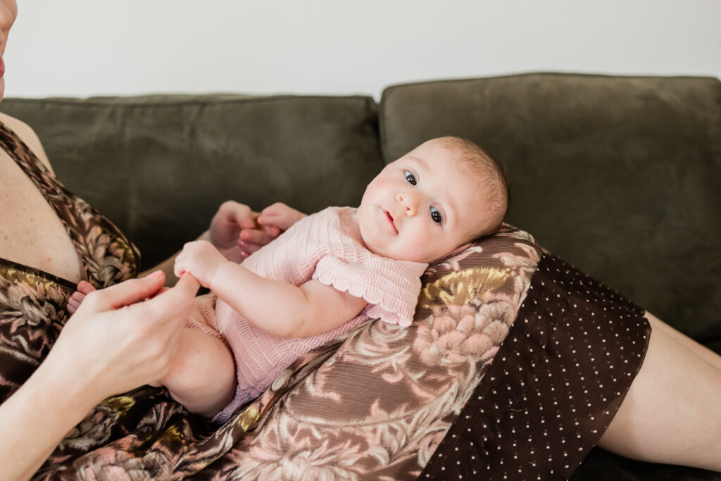 baby girl smiling and laying in mother's lap
