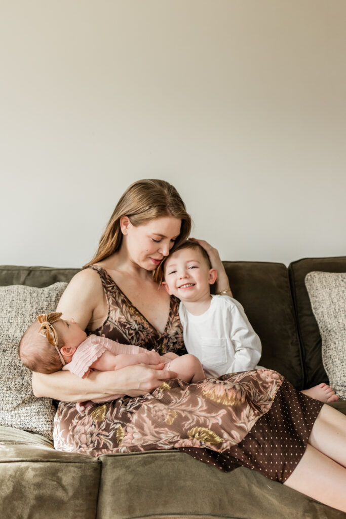 Including Toddlers in Newborn Photo Sessions - toddler sitting on sofa next to woman and baby girl

