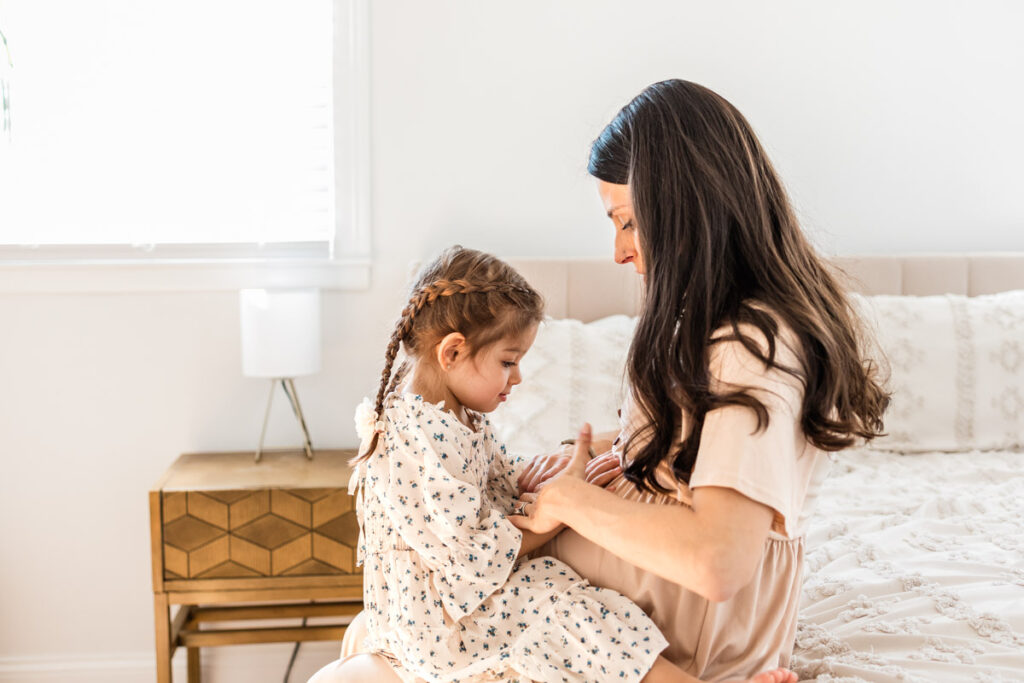 Toddler touching mom's pregant belly during in-home maternity session